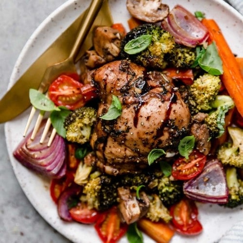 Overhead view serving of sheet pan balsamic chicken and veggies on plate with gold cutlery