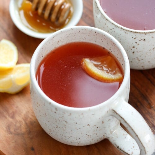 Two mugs filled with homemade Starbucks Medicine Ball Tea on a round wooden tray.